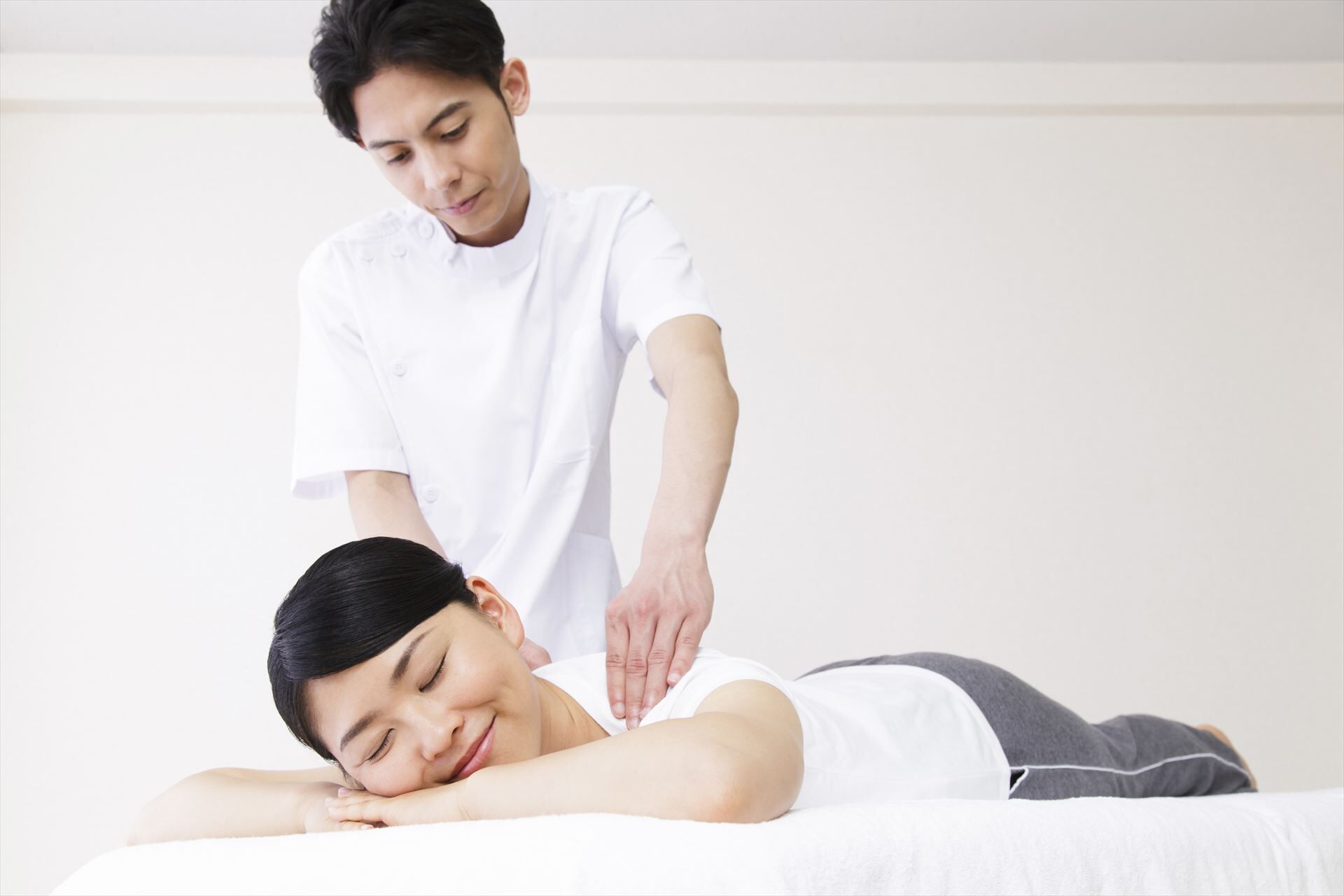 女性の体をほぐす男性スタッフ