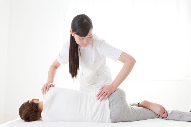 女性の腰を伸ばすスタッフ